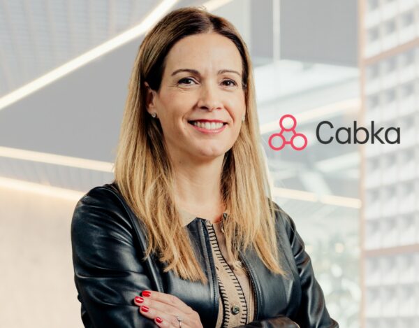 A woman with long light brown hair and a black leather jacket stands smiling with arms crossed in front of a Cabka company logo.