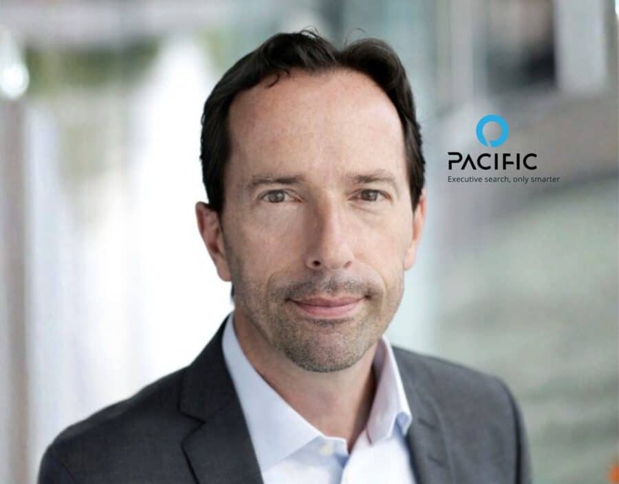 A man in a business suit stands indoors with a neutral expression; the Pacific company logo and slogan are visible in the background, highlighting his role on the Advisory Board.