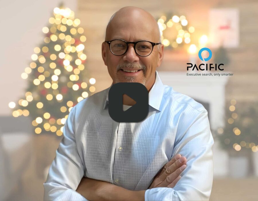 Bald man with glasses smiling, wearing a light shirt, stands in front of a blurred Christmas tree; Pacific logo and slogan appear on the right.