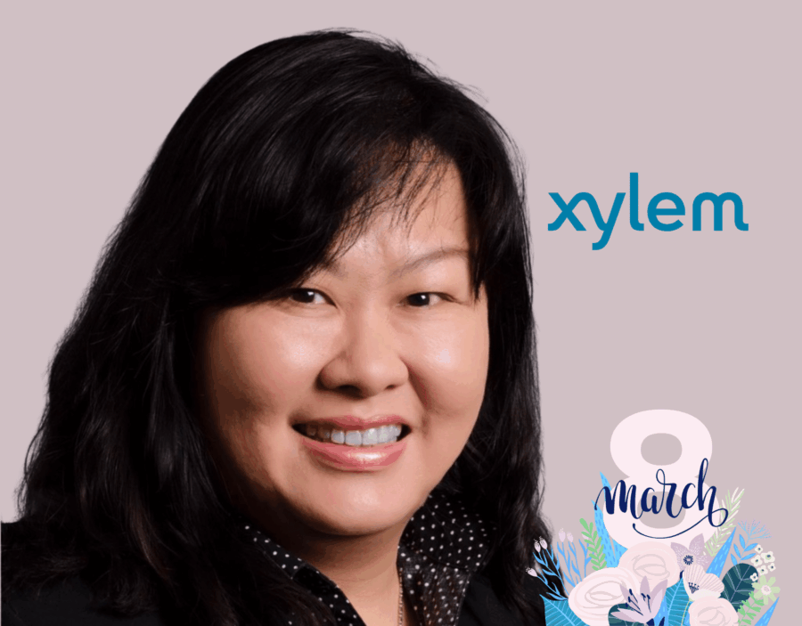 A woman smiling in front of a light background with the Xylem logo and "8 March" International Women’s Day graphic in the corner.